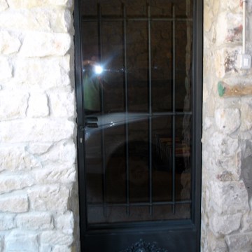Puerta de forja de exteriores con vidrio transparente y elementos decorativos