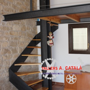 Escalera de caracol con peldaños de madera y altillo de diseño con acero pintado de forja y barandilla de sirga horizontal