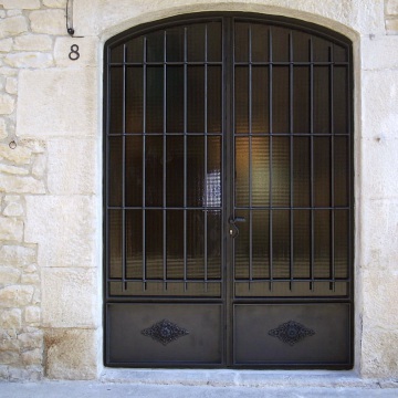 Puertas batientes de dos hojas, con arcada, forjadas, con vidrio armado y con ornamentos decorativos